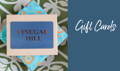 A Vinegar Hill gift card, which has gold coloured logo against a petrol blue background. Shown sitting on a plain card, on top of a patterned card on a green and white patterned background.